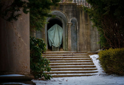 Ghostly figure of a tarp over a statue unser the stairs