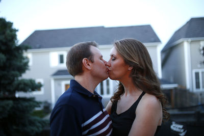 Romantic couple kissing while standing in patio against house