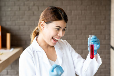 Cheerful young woman holding test tube