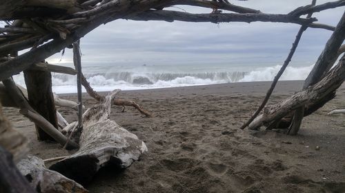 Sea waves splashing on beach against sky