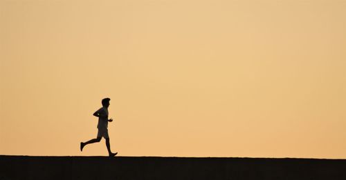 Silhouette man against clear sky during sunset