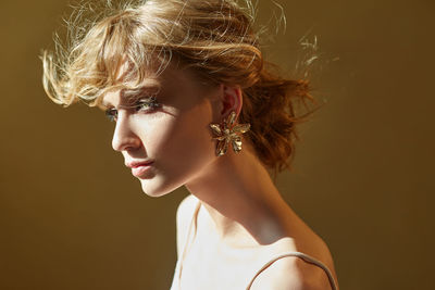 Close-up of beautiful woman looking away against beige background