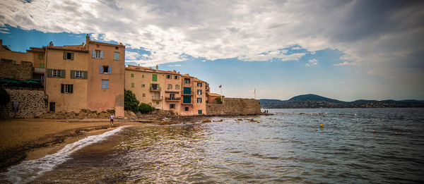 Buildings by sea against sky