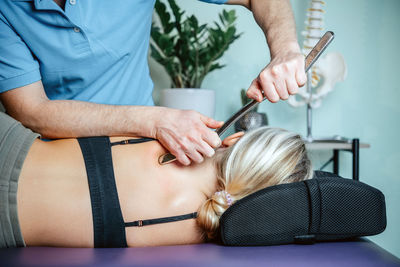 Chiropractor performing myofascial release techniques with iastm tool for the rhomboids