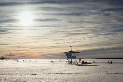 The life guard's hut is standing in guard while people are enjoying a beautiful day on the seaside. 