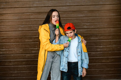 Portrait of young woman standing against wall