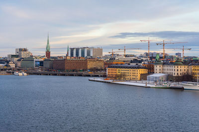 River by buildings in city against sky