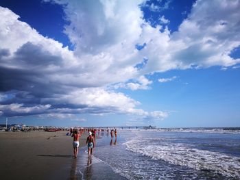 People walking on beach against sky