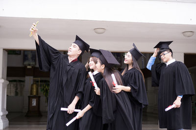 Students in university gowns taking selfie