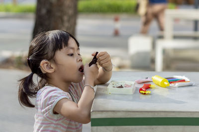 Close-up of cute girl playing with childs play clay at table outdoors