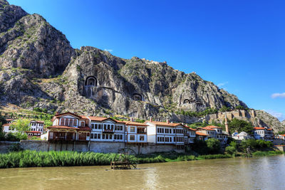 House by lake and buildings against clear sky