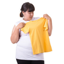 Woman holding yellow t-shirt against white background