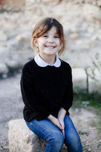 Portrait of smiling girl sitting outdoors