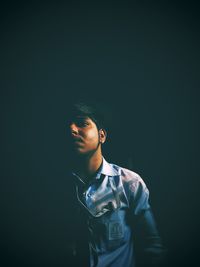 Young man looking away over black background