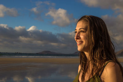 Portrait of smiling woman looking away against sky