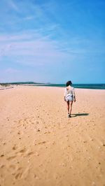 Rear view of woman on beach against sky