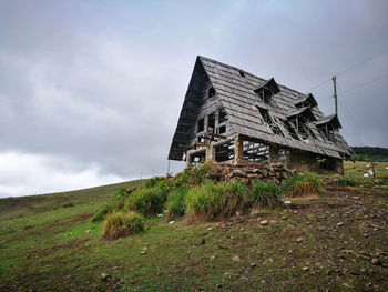 Abandoned house on field against sky