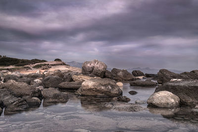 Rocks on sea shore against sky