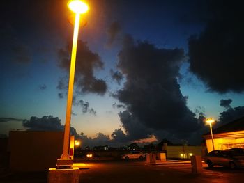 Illuminated street light against sky at night