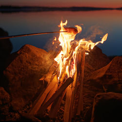Close-up of bonfire on rocks during sunset