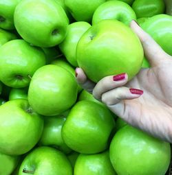 Close-up of cropped hand holding granny smith apple at market stall
