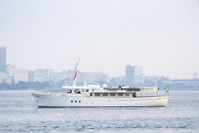 Nautical vessel on sea by buildings against clear sky