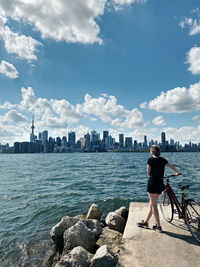 Rear view of woman looking at sea by buildings against sky