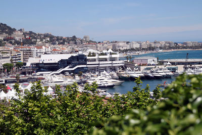 Boats moored in harbor by city against sky