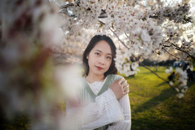 Portrait of young woman standing against trees