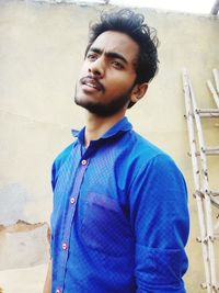 Portrait of young man standing against wall