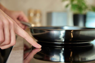 Woman turn on induction hob with frying pan