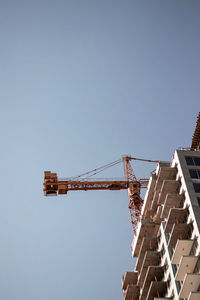 Low angle view of crane against clear blue sky