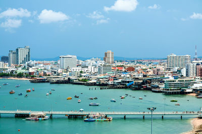 Boats in sea by buildings in city against sky