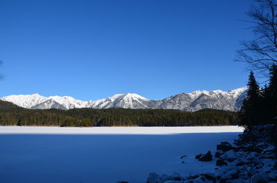 Scenic view of lake and mountains against clear blue sky