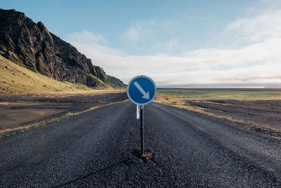 Road sign by mountain against sky