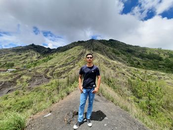 Full length portrait of man standing on mountain against sky