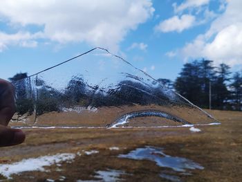 Person holding umbrella on snowcapped mountain against sky