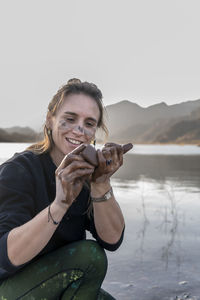 Woman putting mud on hands and face while enjoying outdoors in nature.