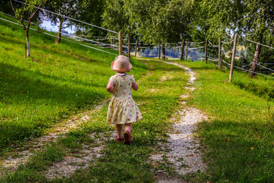 Rear view of woman walking on grassy field