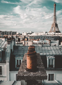 Eiffel tower in city against cloudy sky