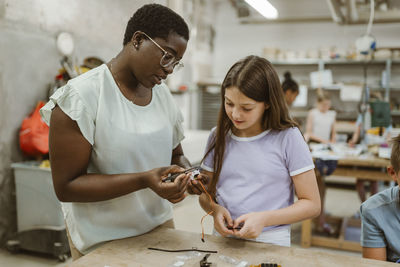 Female teacher explaining electrical part to student at technology workshop in classroom