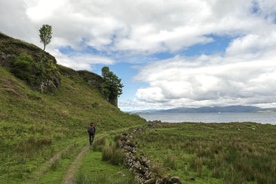 Rear view of man standing on mountain against sky