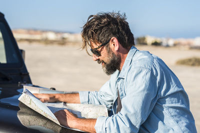 Side view of young man using laptop while sitting in car