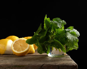 Yellow ripe lemon and a bunch of fresh green mint on a wooden board, ingredients for lemonade