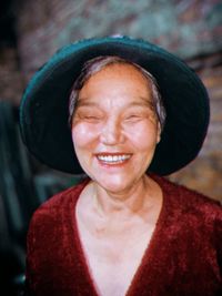 Close-up of smiling senior woman against wall