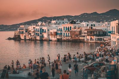 People by sea against sky during sunset