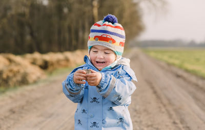 Cute boy looking away while standing on field