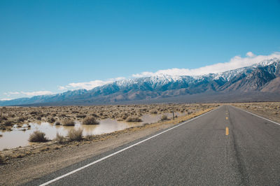 Road by mountains against clear blue sky