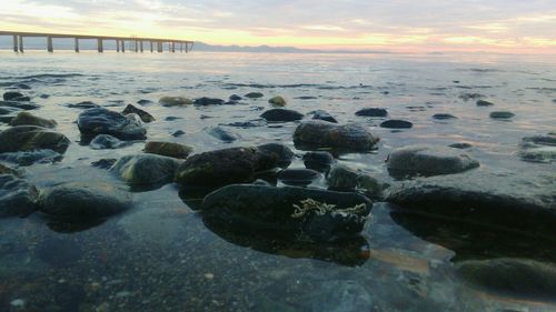 Rocks on beach against sky during sunset