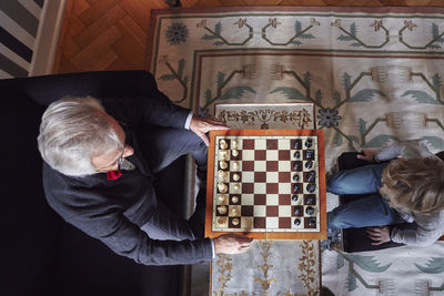 Grandfather and grandson playing chess in living room